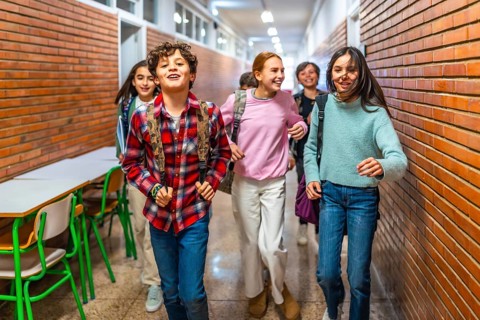 Cheerful students with backpacks rushing through the school hallway, enjoying their break between
