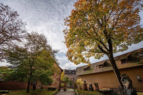Cemetery with autumn tree at St. Nicholas and St. Ulrich Church, Kirchenberg 15,