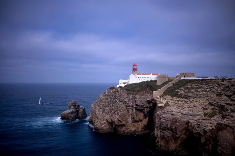 Sailing boat in front of the lighthouse Farol do Cabo de São Vicente, Cape St. Vincent, Sagres,