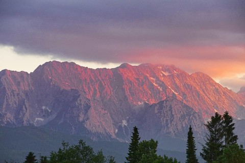 Mountain peak in bright red at sunset with dramatic clouds in the sky, Wallgau, Bavaria, Germany,