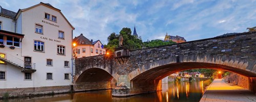 Town view of Vianden with the old stone bridge over the river Our and the castle in the evening,