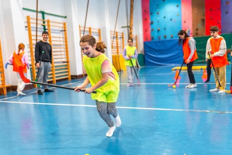 Elementary school children playing floorball in gym class, learning teamwork and sportsmanship