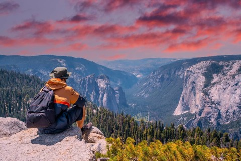 A young winged seated Taft point looking at Yosemite National Park and El Capitan in sunset. United