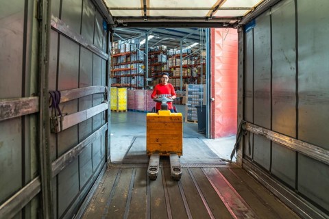 Views from inside the vehicle of a latin worker at a distribution warehouse loading boxes on a