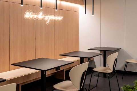 Empty tables and chairs illuminated by modern light fixtures create a workspace in an airport
