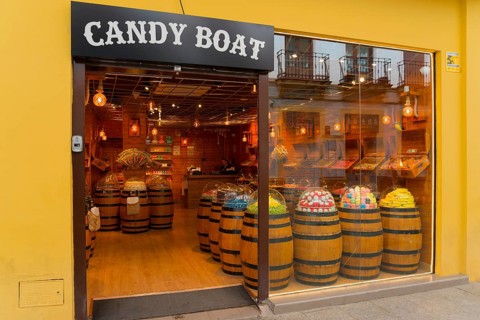 Confectionery shop with wooden barrels full of sweets and a yellow façade presenting a tempting