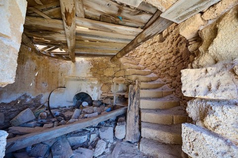 The interior of an old, abandoned mill with stone staircase and decaying wooden beams, windmill,
