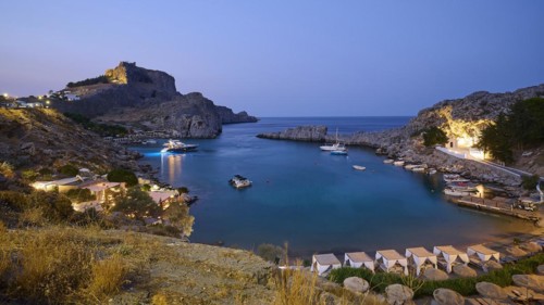 St Paul's Bay in the evening light, view of an illuminated bay with boats and calm water at dusk,