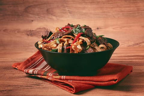 Udon noodles with beef in Mongolian style, with green onions and vegetables, served in a black