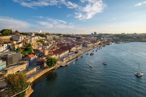 View of Vila Nova de Gaia city and Douro river with tourist boats on sunset. Porto, Portugal,