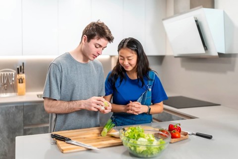 Multiethnic couple joyfully preparing a vibrant, healthy salad together in their modern kitchen,