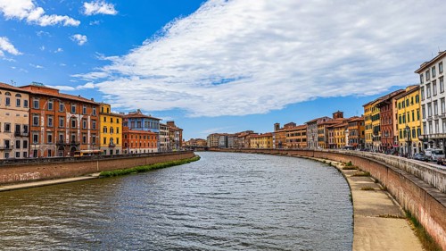 Rows of houses with pastel-coloured facades to the left and right of the River Arno, Pisa, Tuscany,