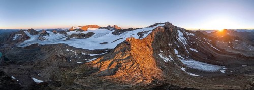 Atmospheric sunrise in a picturesque mountain landscape, alpenglow, aerial view, mountain hut