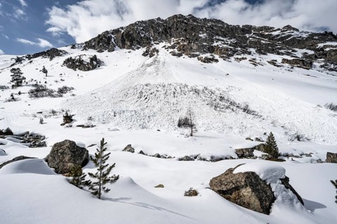 Avalanche cone of a wet snow avalanche on a steep mountain slope with little snow, Bündner Haute