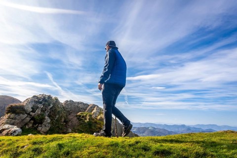 Male hiker using a walking stick while enjoying a sunny day on the summit of mount penas de aya or