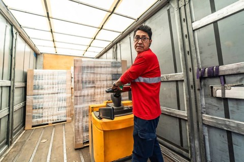 Rear view of a concentrated latin man worker loading a delivery truck in distribution warehouse