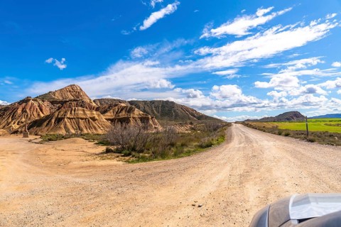 Scenic view of a dirt road winding through the geological formations of bardenas reales desert in