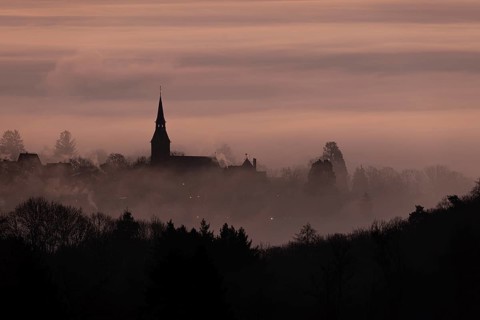 Wisps of mist drift into the town of Kronberg im Taunus in the morning shortly in front of sunrise.