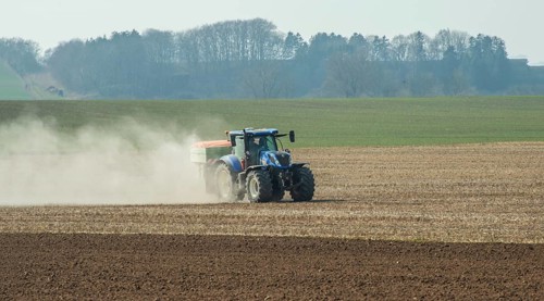 Spring farming, spreading fertilizer with tractor on field in Ystad municipality, Skåne county,