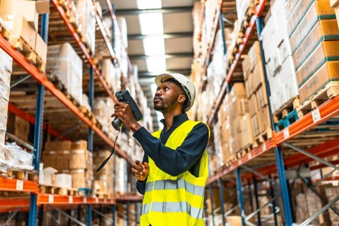 African man using scanner to read the barcodes and check the packages in a warehouse