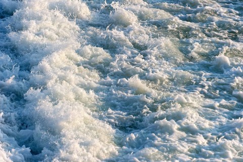 Agitated white foaming water, spray on cascades at the Lech weir, river Lech, background, Landsberg
