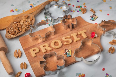 Cheers lettering made from biscuit dough on a wooden board, baking accessories, cookie cutters