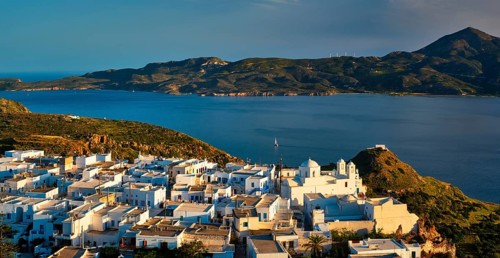 View of Plaka village on Milos island with traditional greek white houses on sunset. Plaka town,