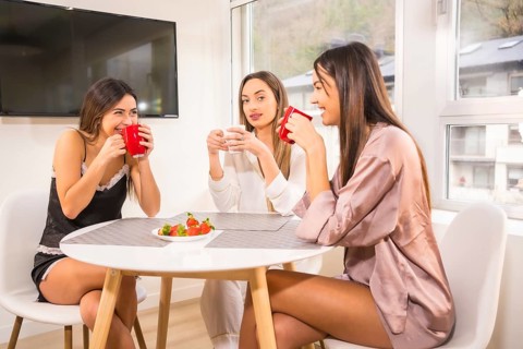 Lifestyle of Caucasian friends on vacation in a hotel having breakfast, dressed in nightwear and