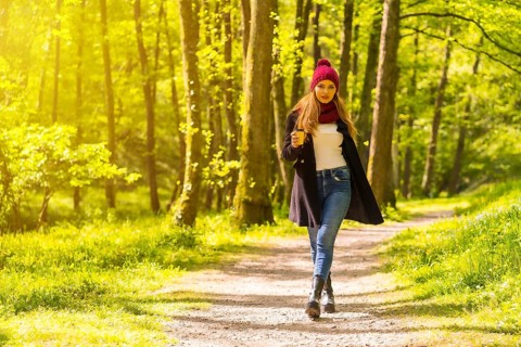 Latin girl with a black jacket, scarf and red woolen hat enjoying in an autumn park, walking along