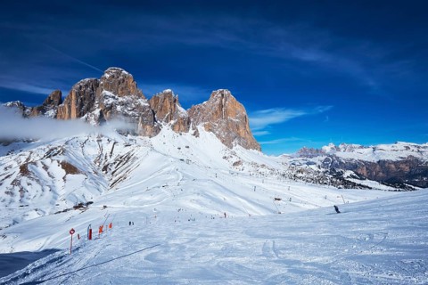View of a ski resort piste with people skiing in Dolomites in Italy
