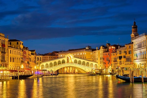 Famous Venetian tourist landmark Rialto bridge (Ponte di Rialto) over Grand Canal illuminated at