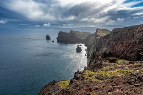 Red cliffs and rocks in the sea, coastal landscape with dramatic sky, Ponta de São Lourenço,