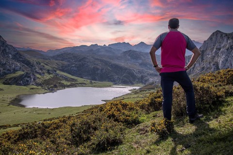 A young man looking at the beautiful Covadonga lake in Asturias in a beautiful spring sunset, Picos