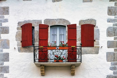 Typical window with balcony, red shutters and potted plants, detail of the façade, Espelette,