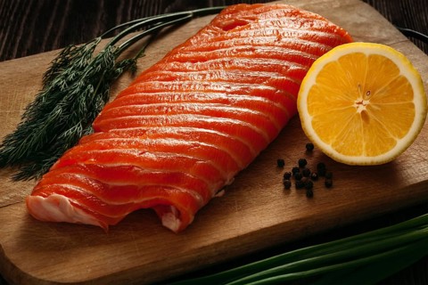 Fresh salmon piece on wooden cooking board with vegetables