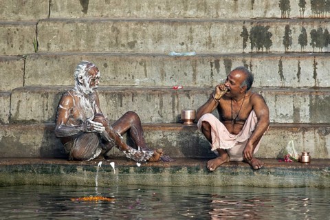 Indian men washing with soap and cleaning teeth at a ghat along the holy Ganges river, Varanasi,