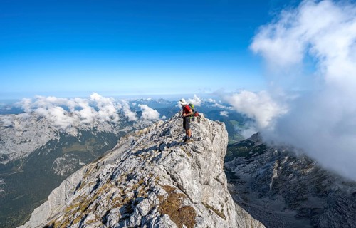 Mountaineer on a rocky narrow mountain path with mountain panorama, mountain tour to the summit of