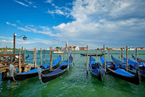 VENICE, ITALY, JUNE 27, 2018: Gondolas and gondolier in lagoon of Venice by Saint Mark (San Marco)