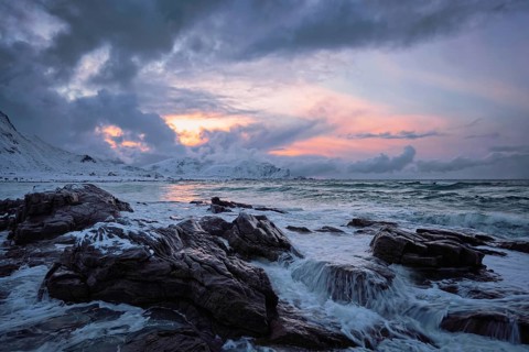 Waves of Norwegian sea on rocky coast in fjord on sunset. Skagsanden beach, Lofoten islands,