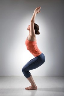 Sporty fit woman doing Surya Namaskar ashtanga vinyasa yoga asana Utkatasana, chair pose