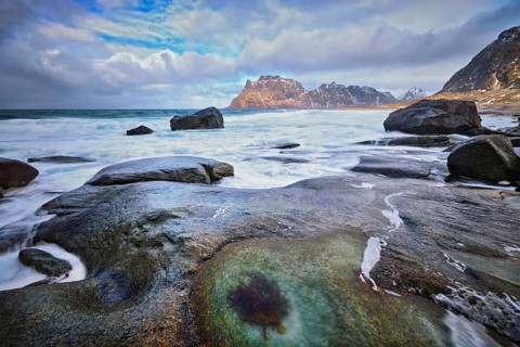 Rocks on beach of fjord of Norwegian sea in winter with snow. Utakliev beach, Lofoten islands,