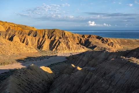 Canyon runs through a landscape of eroded hills at sunrise, Badlands, Issyk Kul Lake in the