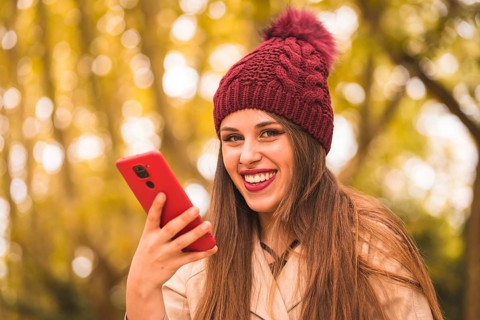 Portrait of a beautiful woman in autumn next to a forest in nature smiling sending a voice note