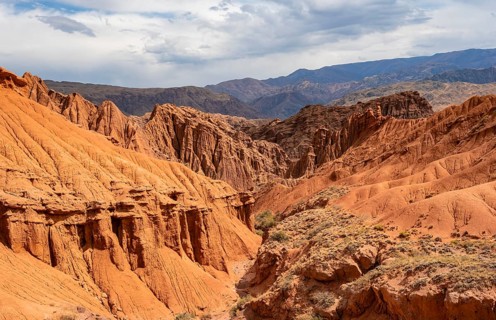 Eroded mountain landscape with sandstone cliffs, canyon with red and orange rock formations,