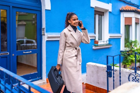 African american beauty friendly businesswoman talking to the mobile leaving the entrance of a blue