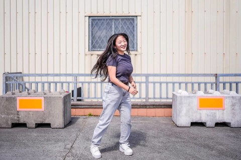Happy asian young woman dancing k-pop alone in the city