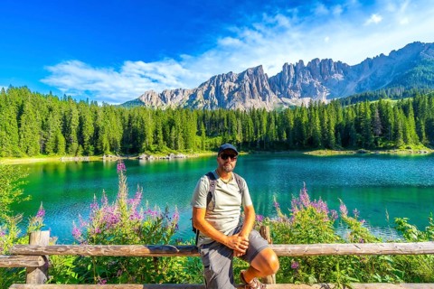 Hiker enjoying the breathtaking view of the emerald waters of lake carezza and the latemar massif