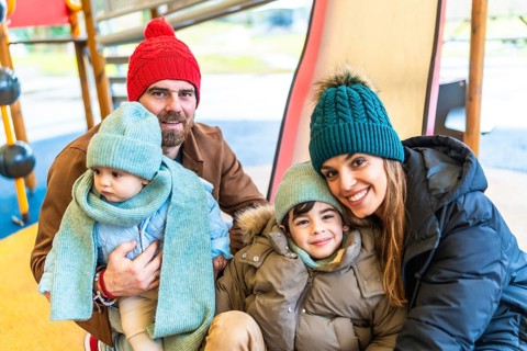 Happy family bundled in winter clothing, smiling and embracing joyfully while enjoying playful