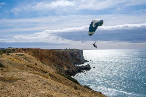 Sagres, Algarve, Portugal - Paraglider flying on the town beach Praia da Mareta, at the back left