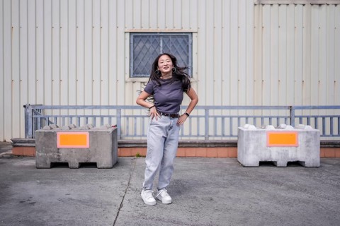 Female asian young K-pop dancer jumping hand on hip performing a choreography in an urban